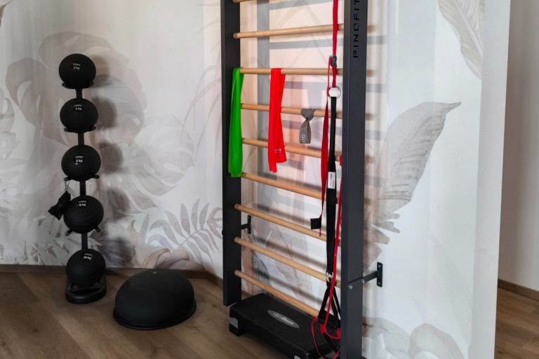 Sprossenwand mit Trainingsbändern, Medizinbällen und Bosu-Ball auf unserer Trainingsfläche.